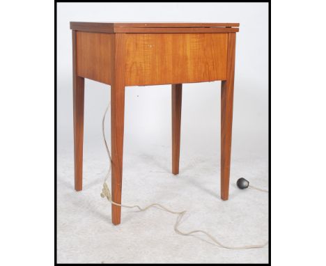 A vintage retro teak wood metamorphic sewing machine wraised on square legs.oak table, having a flip over action 