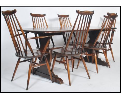 A set of six Ercol Elm and beech stick back dining chairs two being carvers together with an Ercol refector dining table. Mea