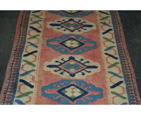 A 20th century carpet / rug runner salmon ground decorated throughout with geometric patterns. Please see images. Measures 39