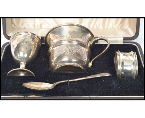 A four piece cased silver hallmarked christening set, consisting of egg cup, beaker, napkin ring and tea spoon. Birmingham as