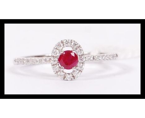 An 18ct white gold ruby and diamond cluster ring, having a central ruby adorned with a halo of diamonds. weighs 2.2 grams siz