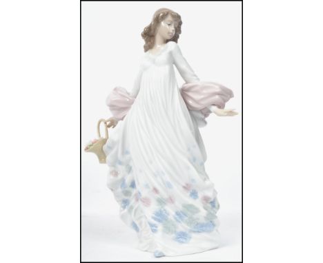 A Lladro ceramic figurine entitled ' Spring Splender ' of a lady holding a floral basket in flowing dress. Measures: 29cm hig