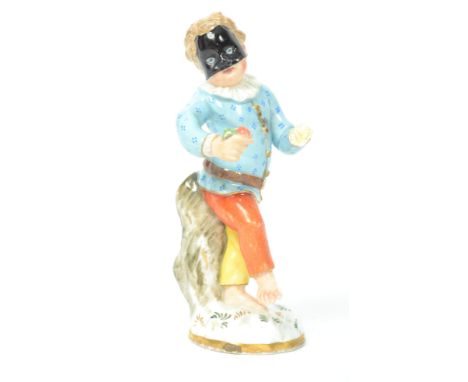 A 18th century Meissen ceramic Masquerade figurine of a boy with mask raised on a circular naturalistic base. Blue crossed sw