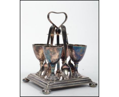A vintage 20th century four person silver plated egg cruet set consisting of four egg cups and spoons mounted on a stepped sq