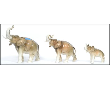 A graduating set of three Royal Dux ceramic elephants with applied pink lozenges to base. The elephants modelled with upturne