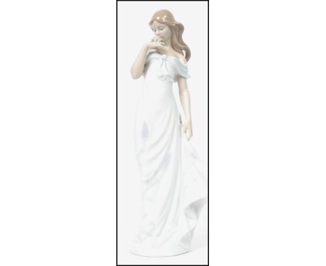 A Lladro ceramic figurine entitled ' A Flowers Whisper ' depicting a lady in a dress holding a flower. The measurements are 3