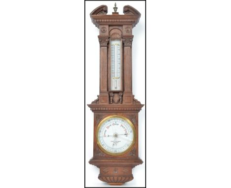 An early 20th century Negretti and Zambra oak aneroid barometer having carved classical columns with arched pediment and bras