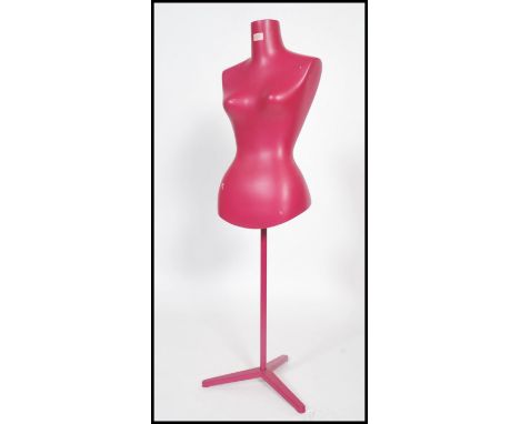 A vintage 20th century advertising shop display mannequin raised on a tripod tubular base painted in a pink finish. Measures: