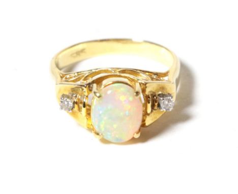 An opal and diamond three stone ring, an oval cabochon opal spaced by diamonds, finger size J.  Stamped '585', 3.8 grams 