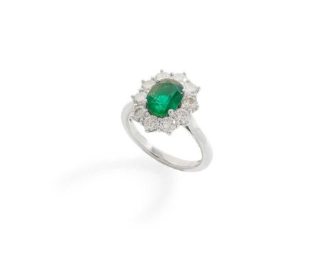 An emerald and diamond cluster ring claw-set with an oval-cut emerald, in a border of ten round brilliant-cut diamonds, model