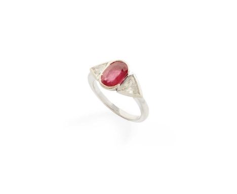 A ruby and diamond three-stone ring part collet-set with an oval-cut ruby flanked to either side by a triangular-cut diamond,