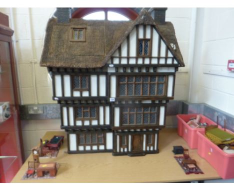 A LARGE WOODEN DOLLS HOUSE MODELLED AS A FOUR STOREY TUDOR HOUSE WITH A THATCH EFFECT ROOF, probably a Robert Stubbs 1/12 sca