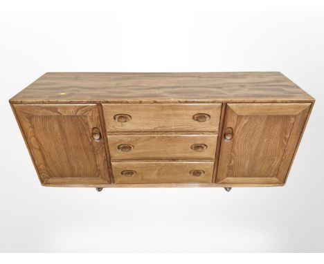 An Ercol elm low sideboard on castors, 155 cm x 44 cm x 69 cm 