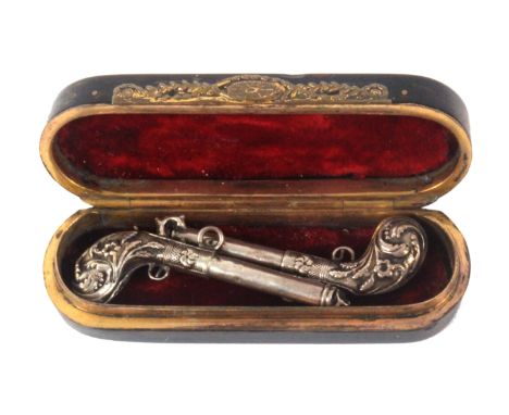 A late 18th Century tortoiseshell and silver inlaid box containing a pair of silver 'charm' pistols, the rectangular rounded 