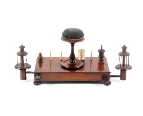 A Regency rosewood 'work stand', the weighted rectangular base raised on four bun feet and fitted with a central turned pin c