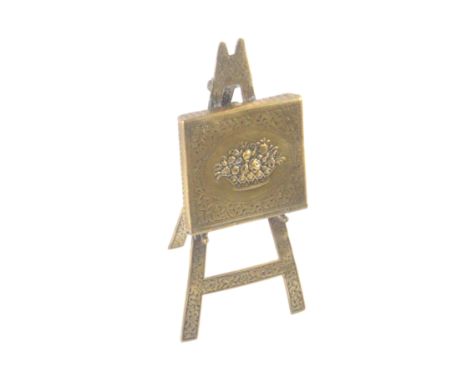 A polished brass Avery needle packet case 'Easel', floral, easel re-soldered to folio, 12cms high.                           