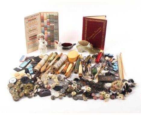 A mixed lot - sewing, comprising a selection of needle packets, bobbins, three ceramic pin cushions, a quantity of buttons, t