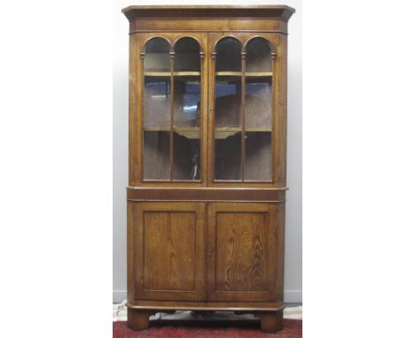 VICTORIAN WELSH OAK DOUBLE CORNER CUPBOARD, having swept cornice over a pair of moulded, glazed doors revealing two shelves t