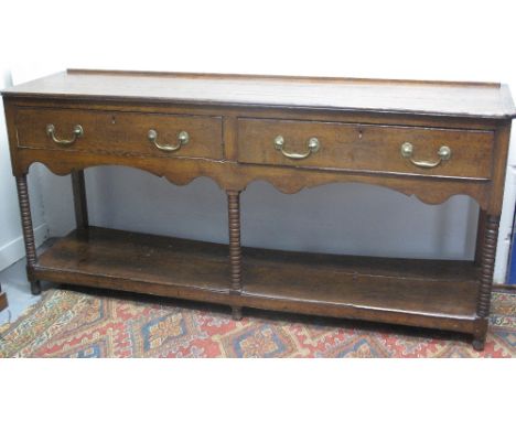EARLY 19TH CENTURY OAK DRESSER BASE, having two frieze drawers above arched apron on bobbin turned supports to the planked po