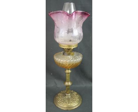 EARLY 20TH CENTURY BRASS DOUBLE BURNER OIL LAMP having wrythen glass reservoir on a brass pedestal with foliate repousse circ