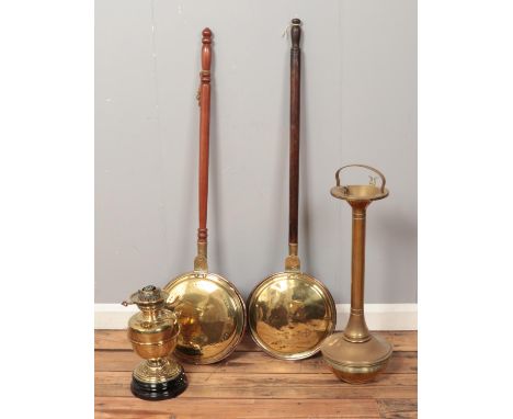 A collection of metalwares. Includes two bed warming pans, a brass smoker's stand and an oil lamp base.  