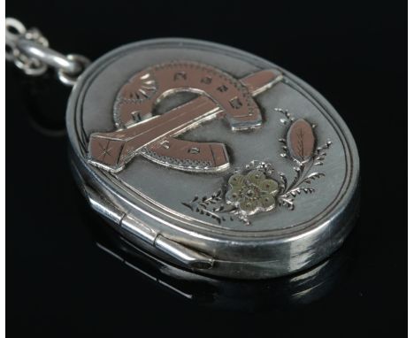 A Victorian gold applied silver locket depicting a horseshoe, on silver chain. Locket assayed for Birmingham, 1892 by S Bros.
