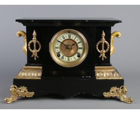 A large black slate mantle clock, with Roman Numeral dial, raised on scrolled gilt metal feet and gilt highlights. Movement s