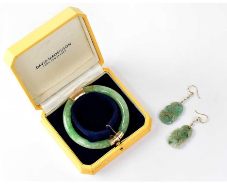 A green jade hinged bracelet with 14k gold mounts and safety chain, together with a pair of green jade drop earrings (2).