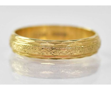 An 18ct gold ring with textured central band, size K, approx. 2.9g.