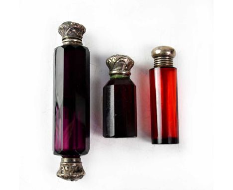 Three Victorian scent bottles comprising a double-ended amethyst glass flask with faceted sides, length 12cm, a small ruby gl