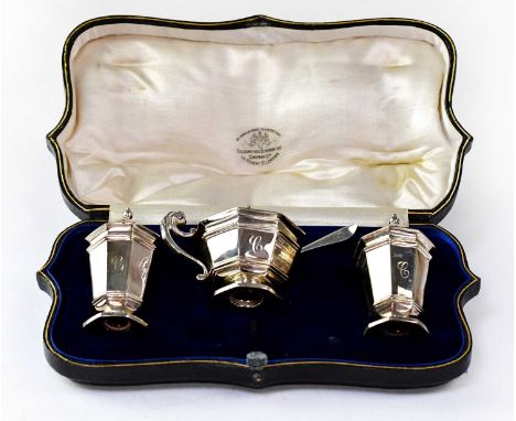 GOLDSMITHS &amp; SILVERSMITHS CO; a George V hallmarked silver three-piece cruet set comprising two peppers, height 10cm, and