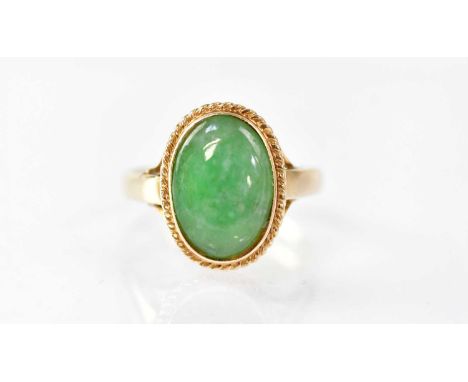 A 14k ring with bezel set oval jade cabochon and beaded border, size N, approx. 3.1g.