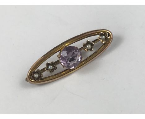 A Belle Epoque amethyst and seed pearl openwork bar brooch, of lenticular form, surmounted by crown and flower head set gemst