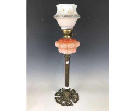 A brass oil lamp with peach glass reservoir