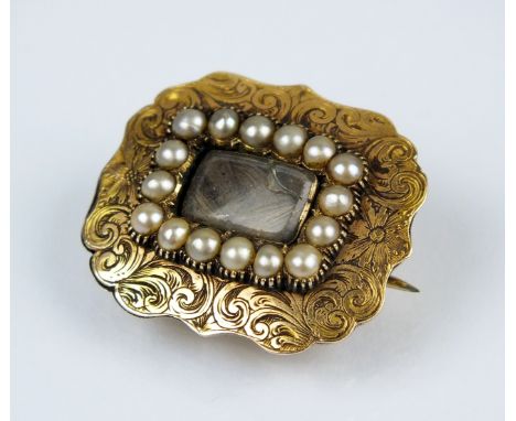 A mid 19th century mourning brooch, designed as a central glazed aperture enclosing plaited hair within a split seed pearl bo
