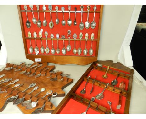 A collection of silver-plated and enamel souvenir teaspoons on three display racks