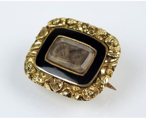 An early 19th century mourning brooch, designed as a central glazed aperture enclosing plaited hair within a black enamel bor