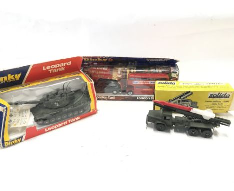 A Boxed Dinky Toys Leopard Tank. #692. a Boxed London Taxi And Bus and a Solido Mobile Rocket Launcher.Boxes worn.