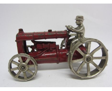 A red painted cast iron tractor with polished metal wheels and driver, in the manner of Arcade, 16.5cm long 