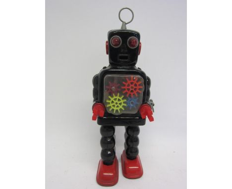 A KO (Yoshiya), Japan, sparking gear robot with black tinplate body and red feet, red plastic arms, clear chest plate with co