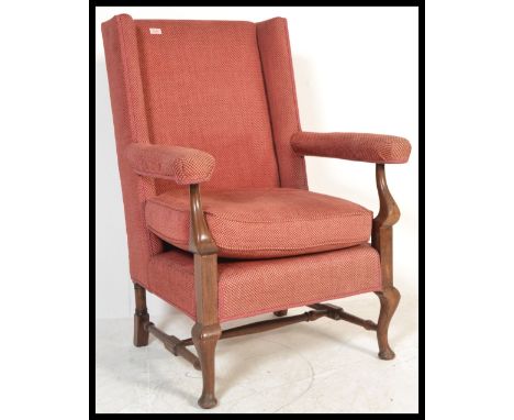 A 19th Century Georgian style wingback armchair, the shaped top rail above a padded back and deep wings, over a loose cushion