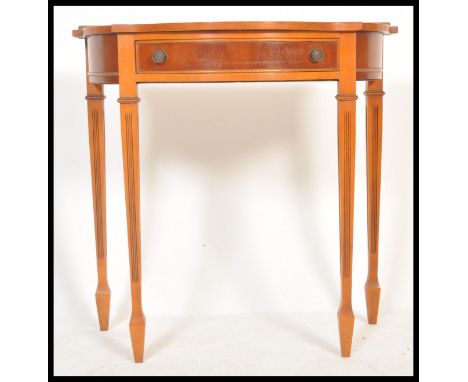 A 20th Century Regency style demi-lune side table having a bow front and single drawer with swing handles, raised on four squ