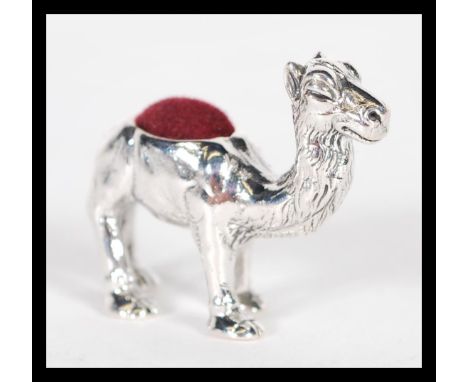 A sterling silver pincushion in the form of a camel having red baize pin cushion to top. Weighs 17 grams.