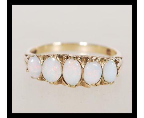 A hallmarked 9ct gold five stone opal ring having a graduating group of five opal panels in decorative pierced scrolled mount