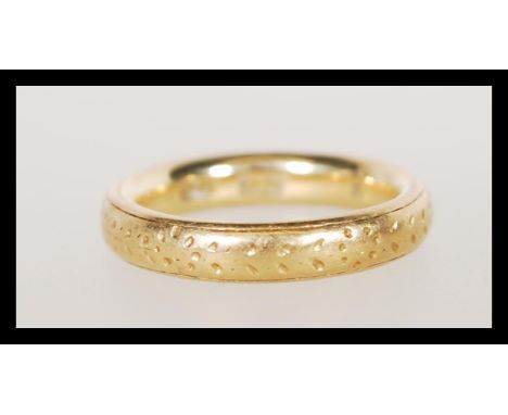 A stamped 18ct gold band ring having floral engraving. Size I. Weight 5.6g.