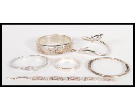 A selection of stamped silver bracelets to include a silver bangle with a hinge clasp, a dolphin bangle, a bangle with rope t
