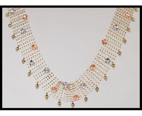 A stamped 375 9ct gold mesh choker style necklace with small silver tone and copper tone flower details. Total weight 16.5g. 