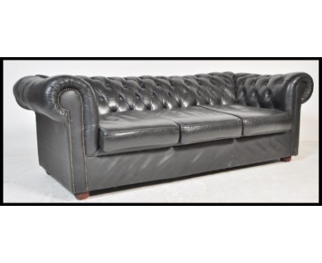 A contemporary black leather button back three seater Chesterfield sofa with button back and scrolled arms on turned supports