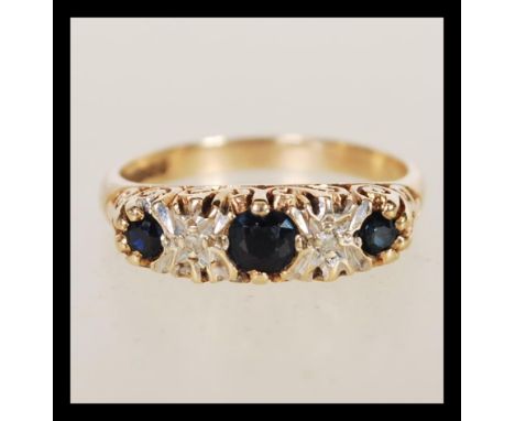 A hallmarked 9ct gold sapphire and diamond ring having alternating faceted blue stones with illusion set diamonds set in pier