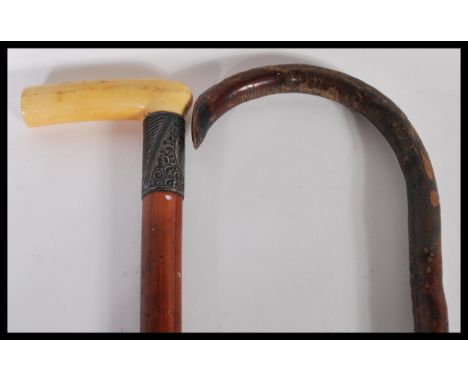 Two walking sticks to include an early 20th Century malacca walking stick having a silver collar and ivory handle to the top 